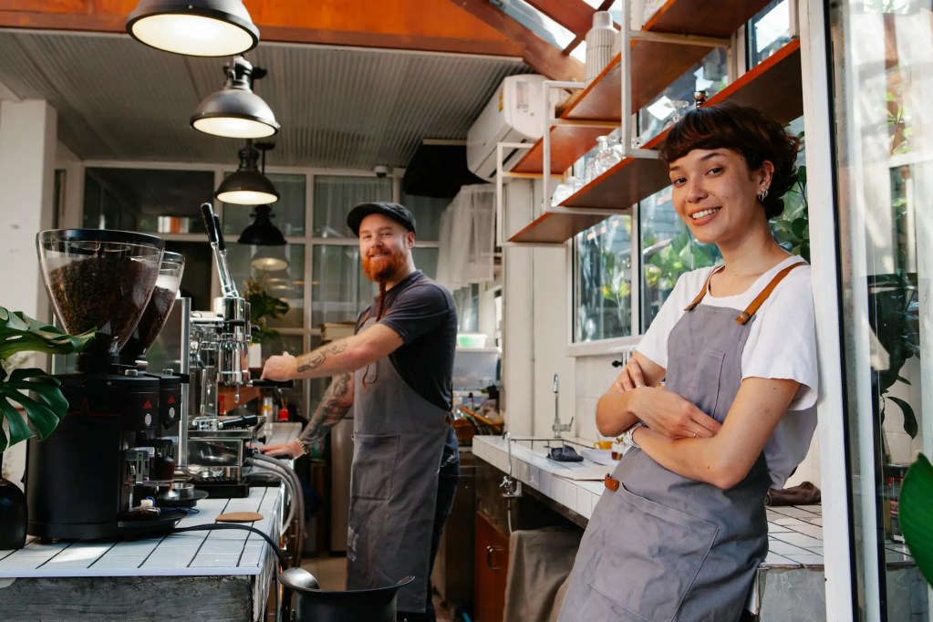 two restaurant owners prepare coffee in their cafe.